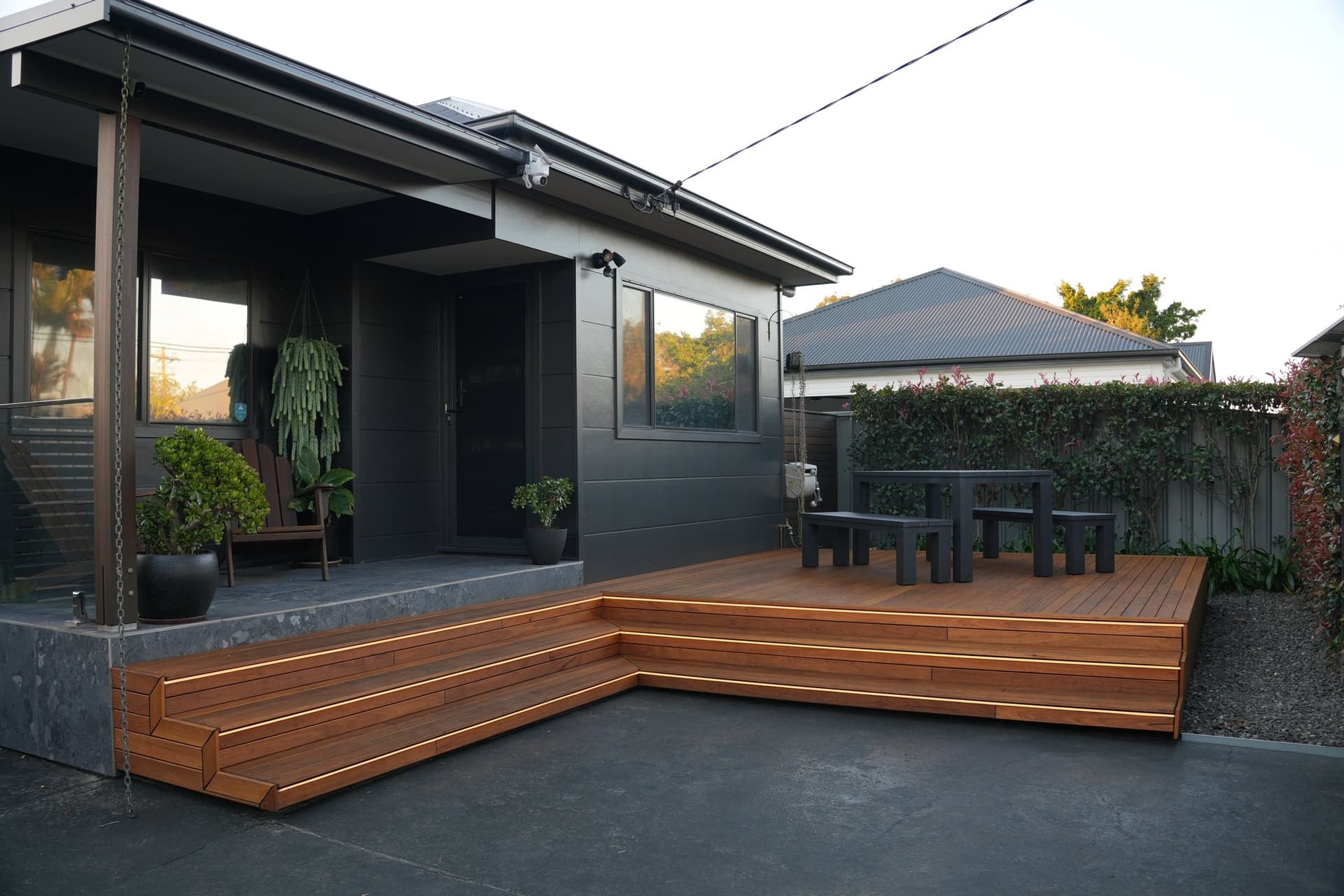 Wide view of a hardwood deck wrapping a dark-clad Newcastle home