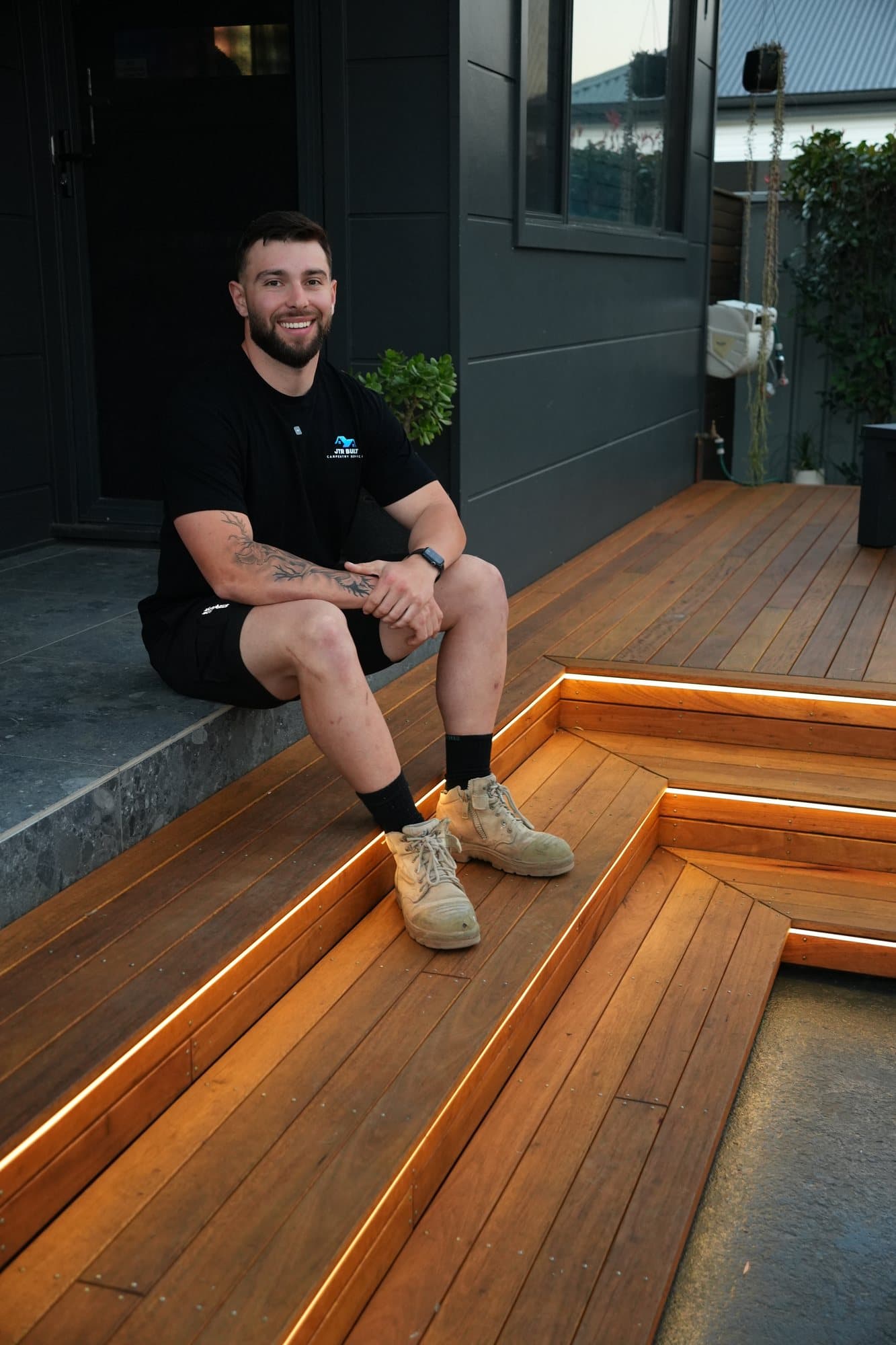James Russo sitting on the lit hardwood steps of a deck he built