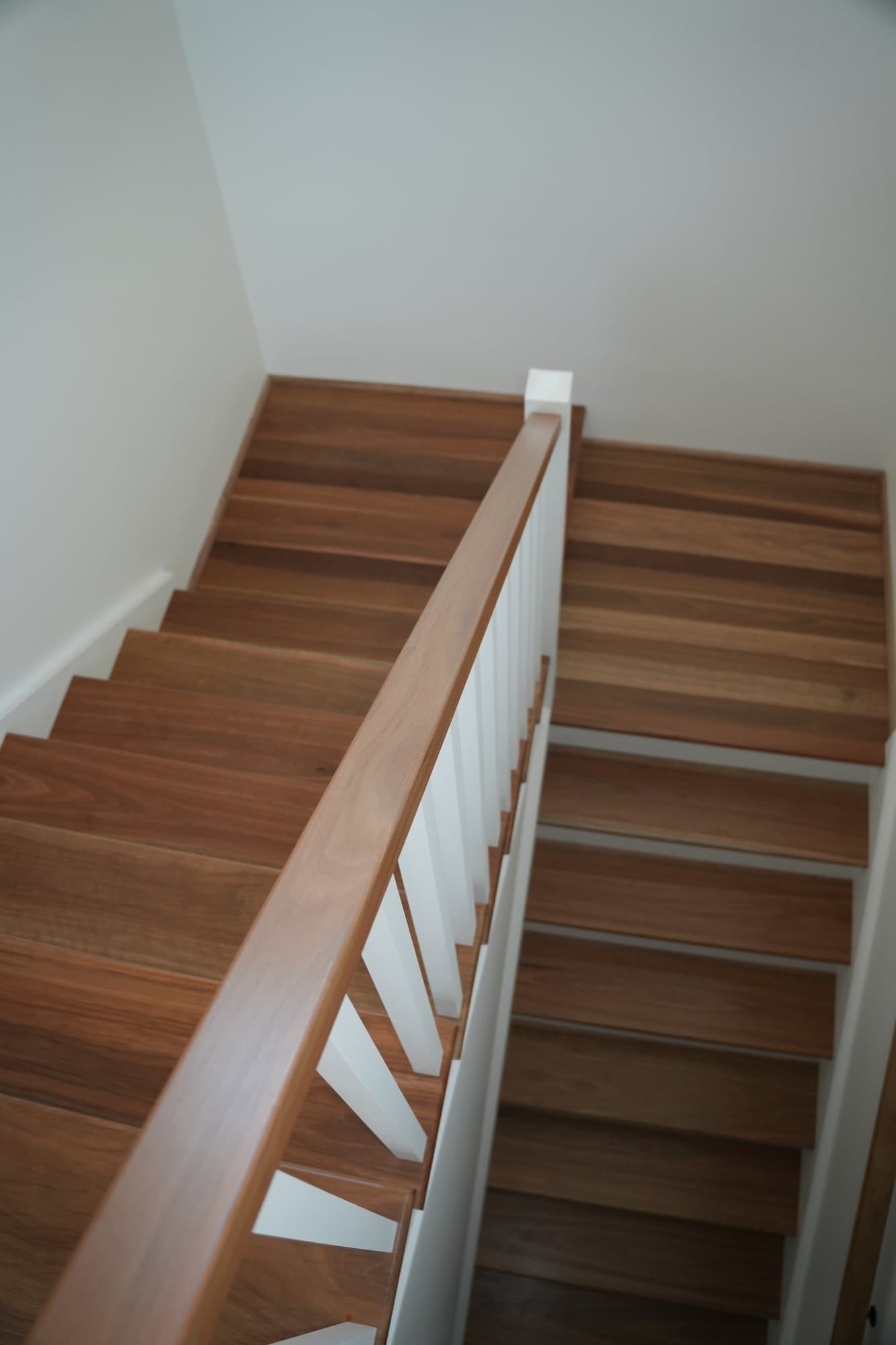 Hardwood staircase with white balustrade and clean risers built by JTR Built