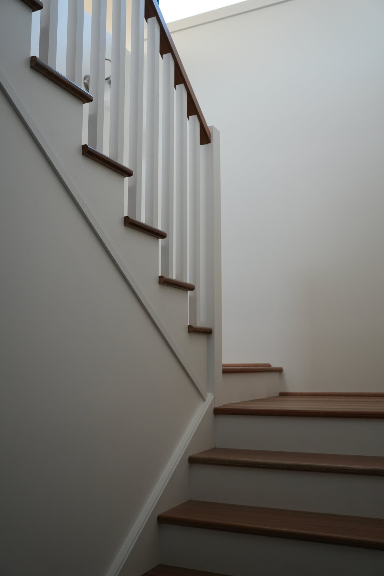 Looking up a hardwood and white staircase built by JTR Built