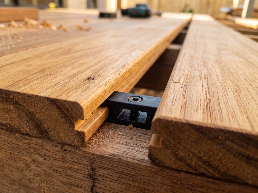 Hidden fixing clip between grooved decking boards